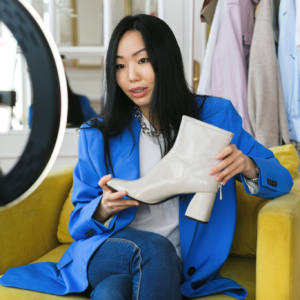 Fashion influencer streaming online reviewing shoes with smartphone and lighting ring.