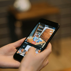 Hands holding smartphone taking a photo of a sale display in a store.